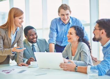 Group of business partners looking at smiling female explaining her ideas at meeting